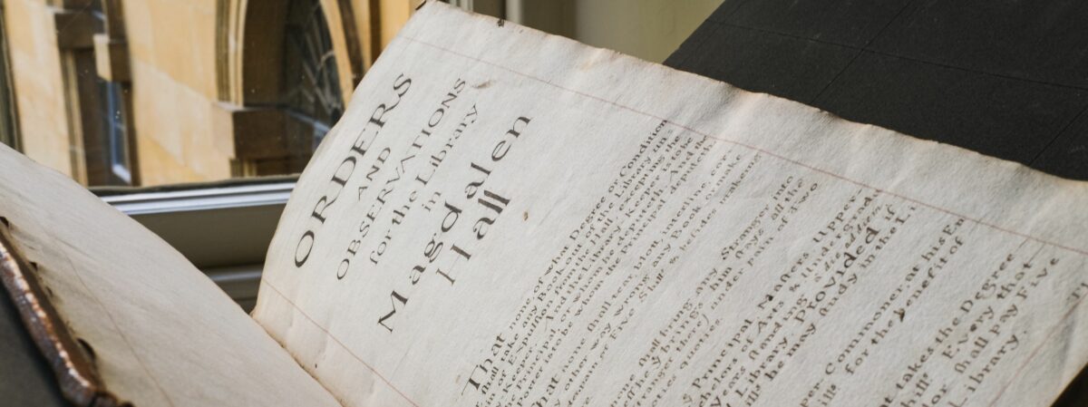 Benefactors Book open to rules page with windows of Hertford Library in background